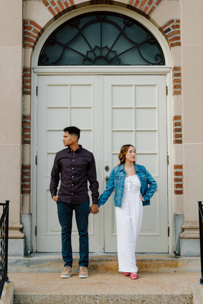 engaged couple holding hands and looking away from camera showing off outfits