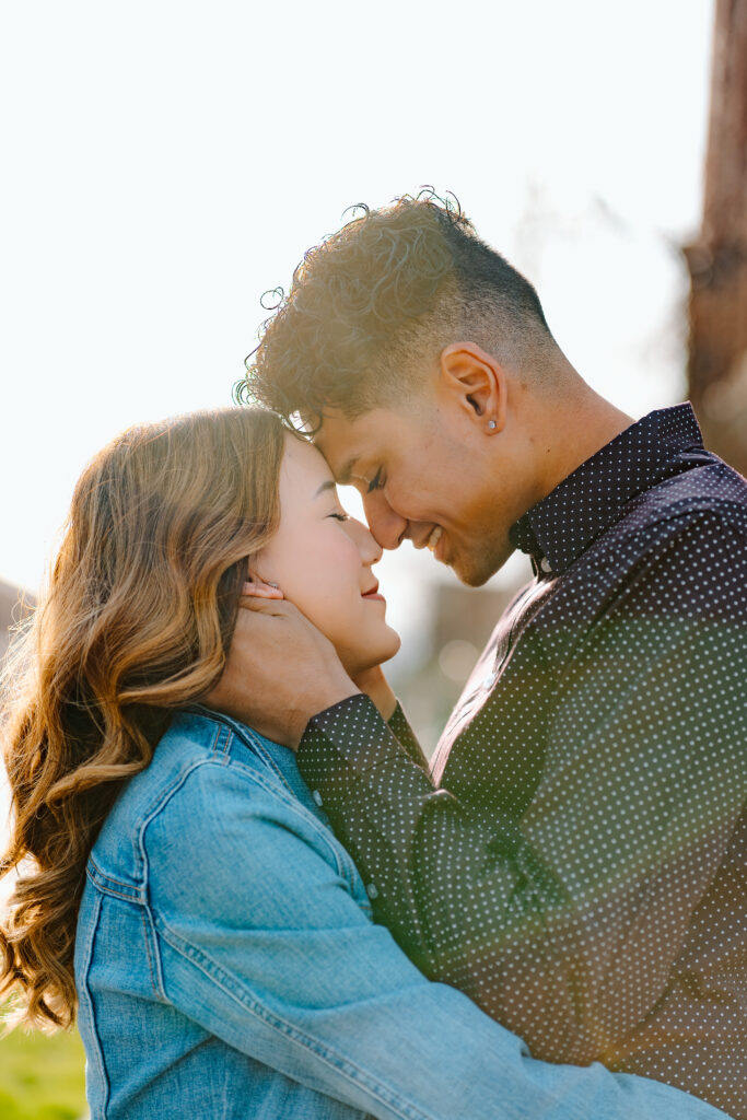 engaged couple touching foreheads during golden hour for engagement photos in michigan