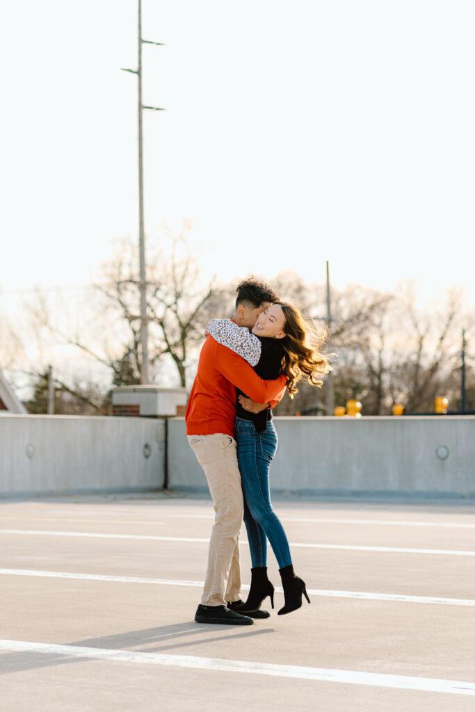engaged couple hugging in an empty parking lot during golden hour