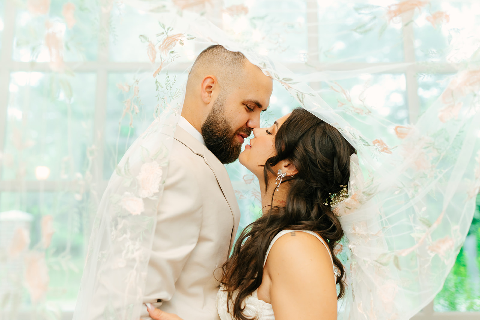 bride and groom eskimo kisses under embroidered veil