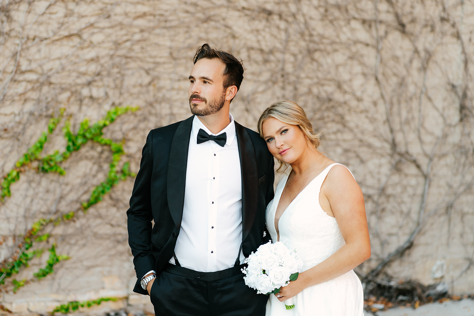 bride and groom formal photo in front of brick wall with vines