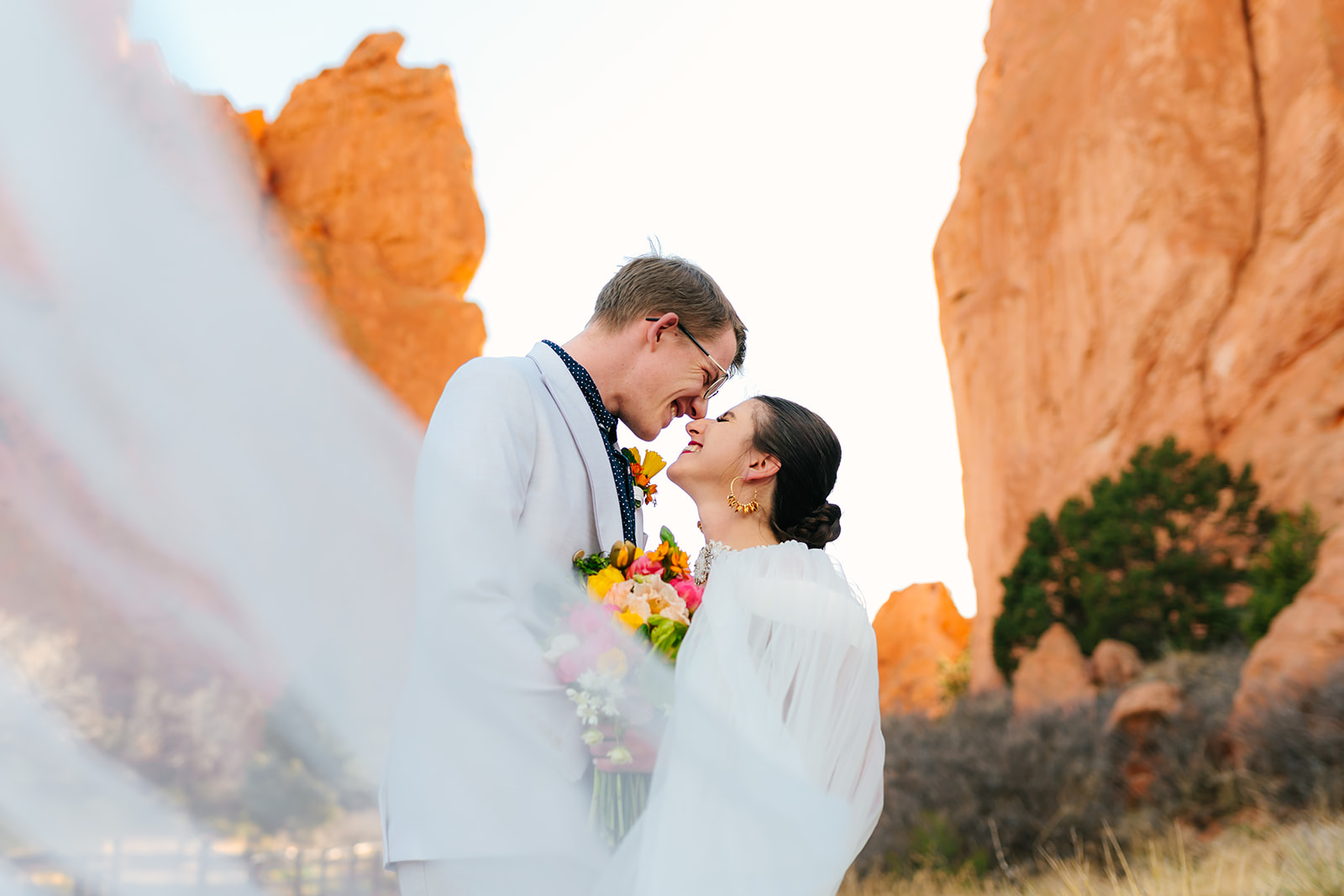 bride and groom posing with red rock canyons at their Garden of the Gods destination elopement in Colorado Springs