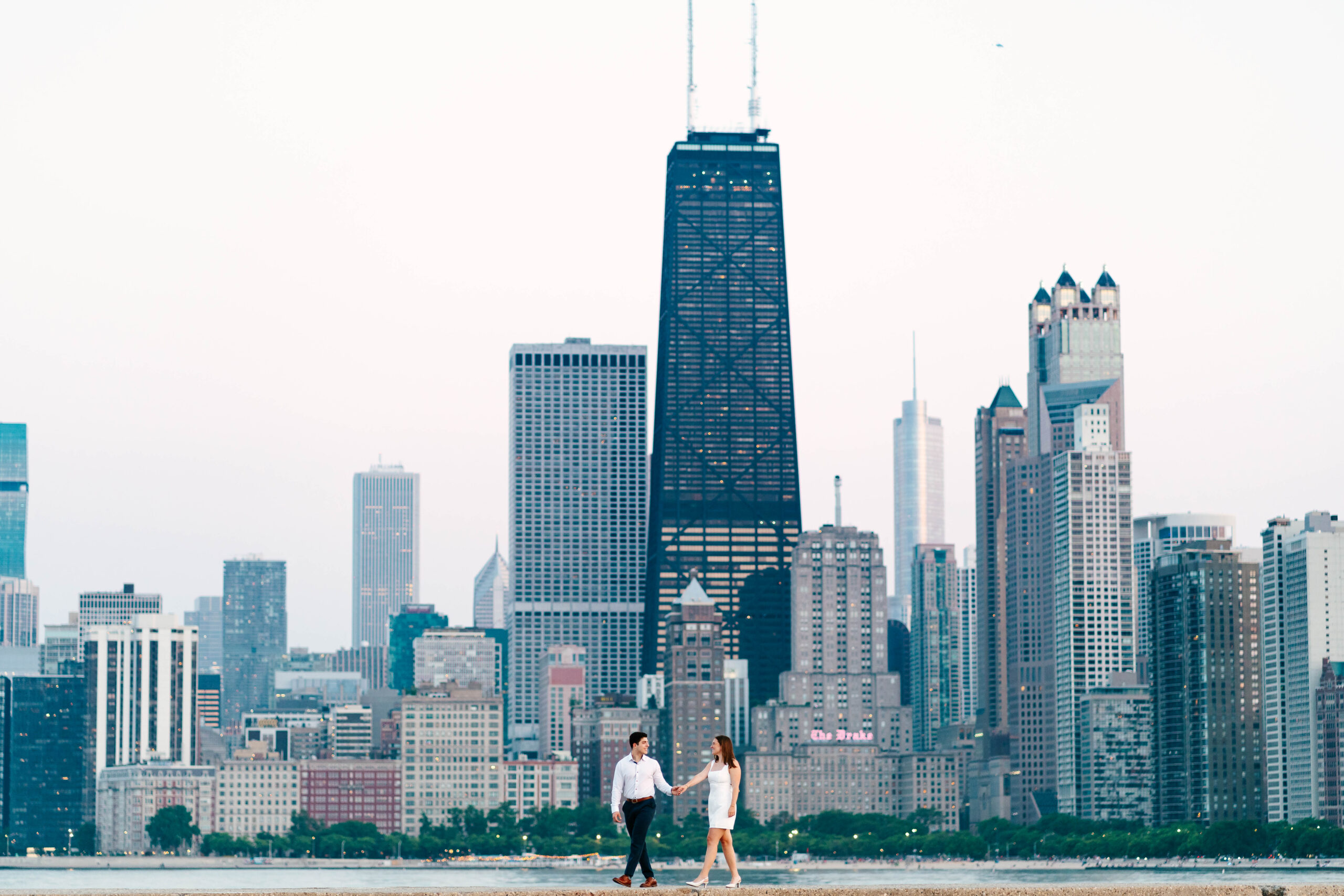 couple walking on north ave beach pier with chicago skyline in the background