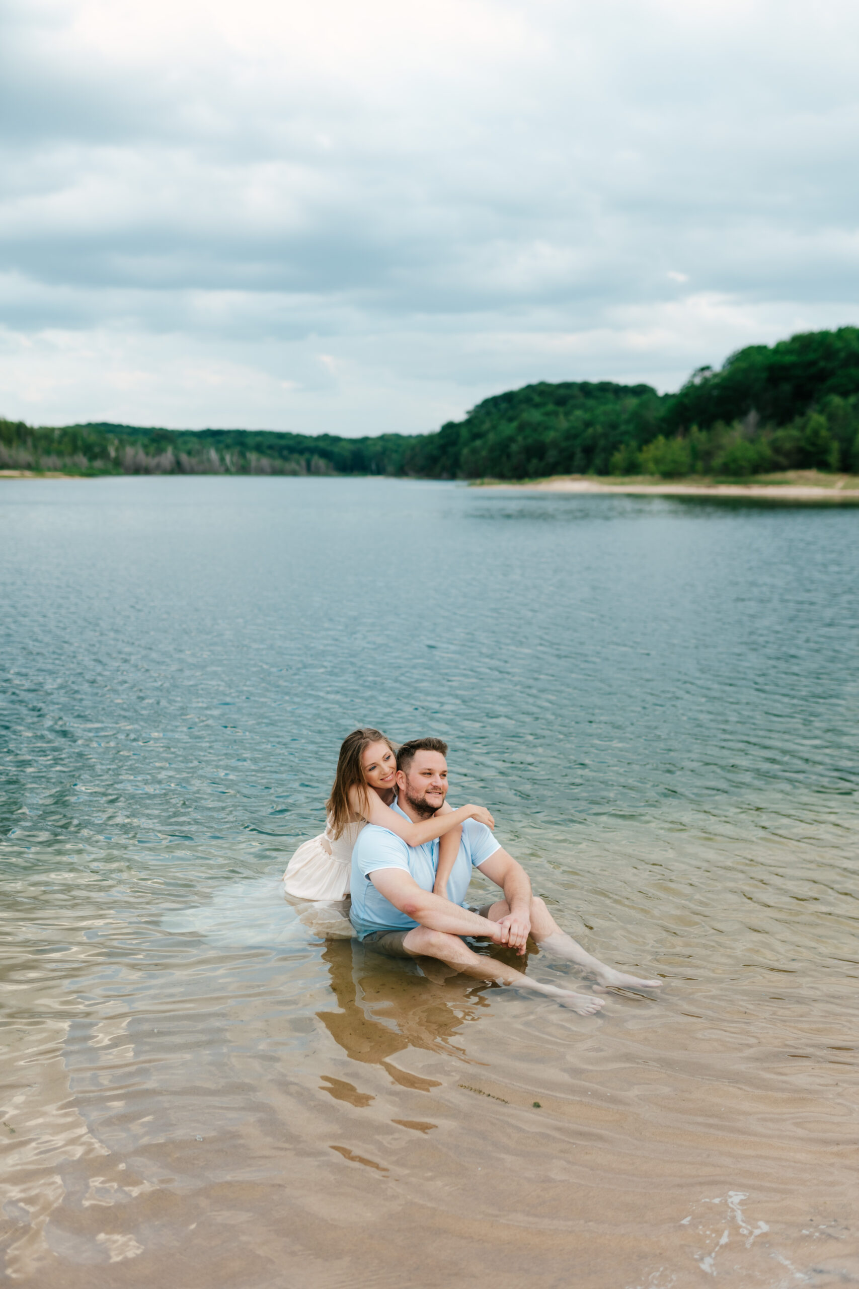 couple sitting in the lake for their engagement photos in northern michigan near sleeping bear dunes