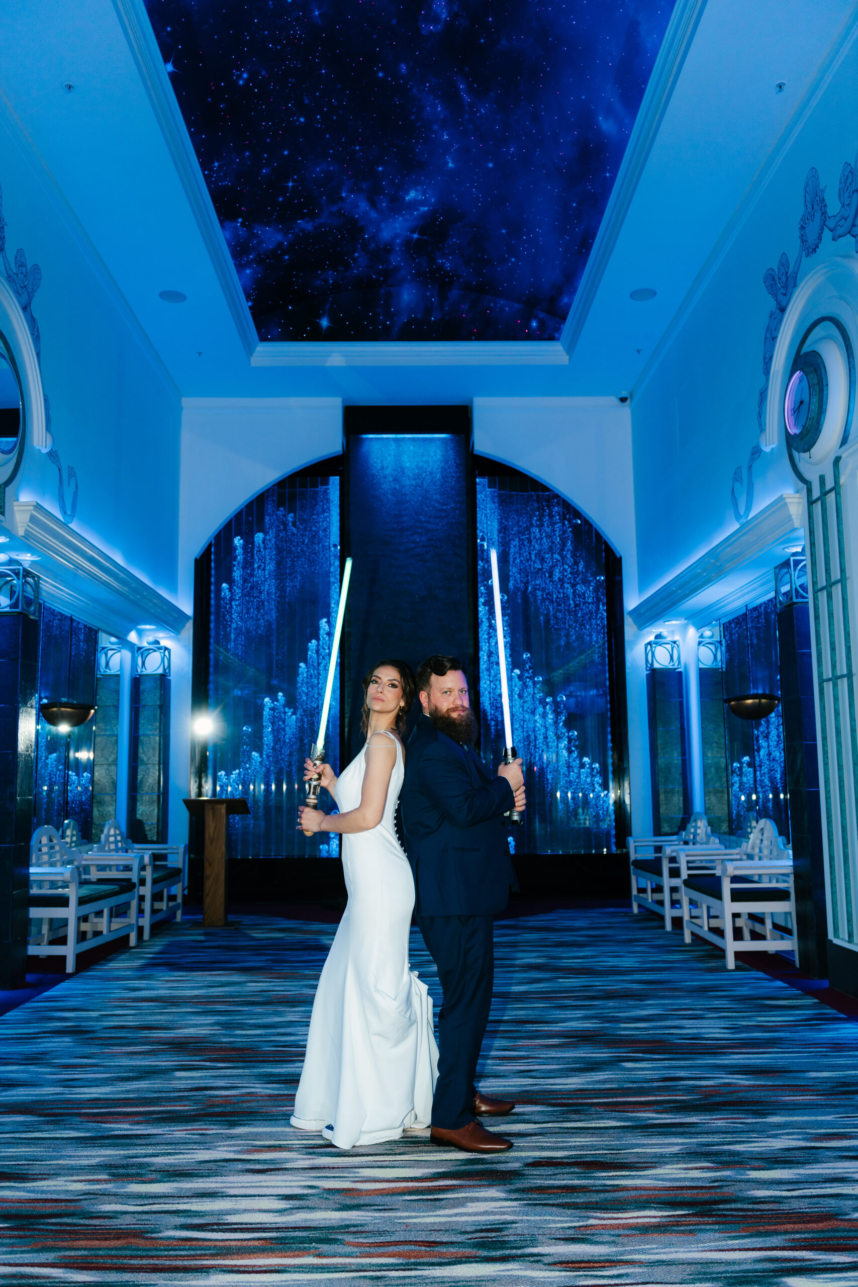 Bride and groom posing with glowing Star Wars lightsabers, playful and cinematic wedding portrait.