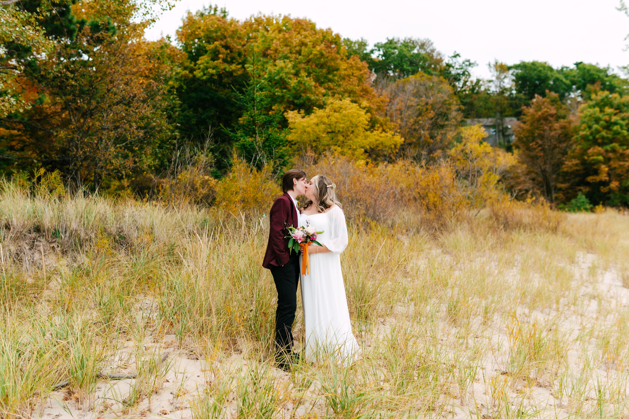 Overcast beach photo of the couple wrapped in each other’s arms.